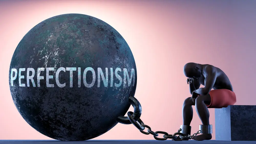 Perfectionism as a heavy weight in life - symbolized by a person in chains attached to a prisoner ball to show that Perfectionism can cause suffering, 3d illustration